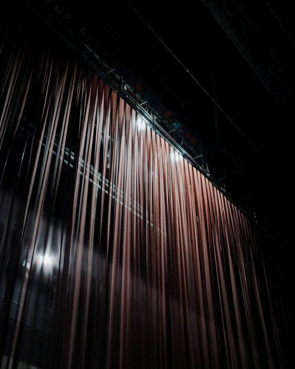 lillian marie. A stage curtain hangs closed in a dark theater.