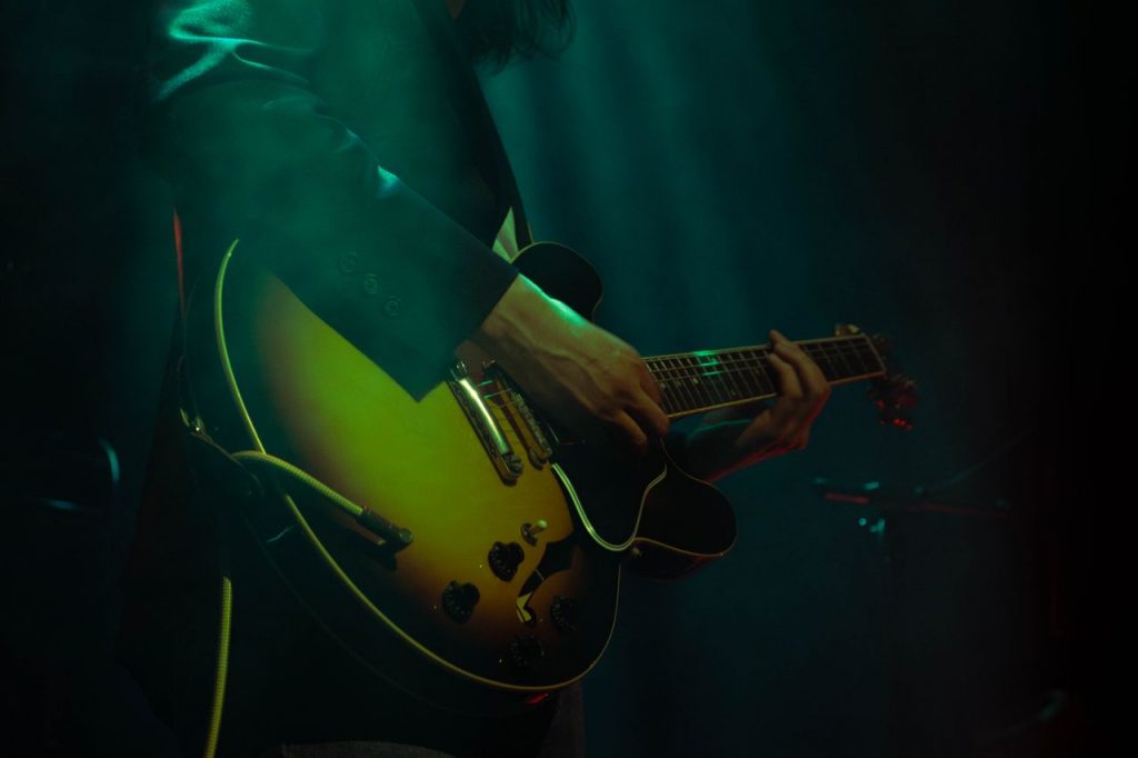 A musician skillfully playing an electric guitar under concert lights.